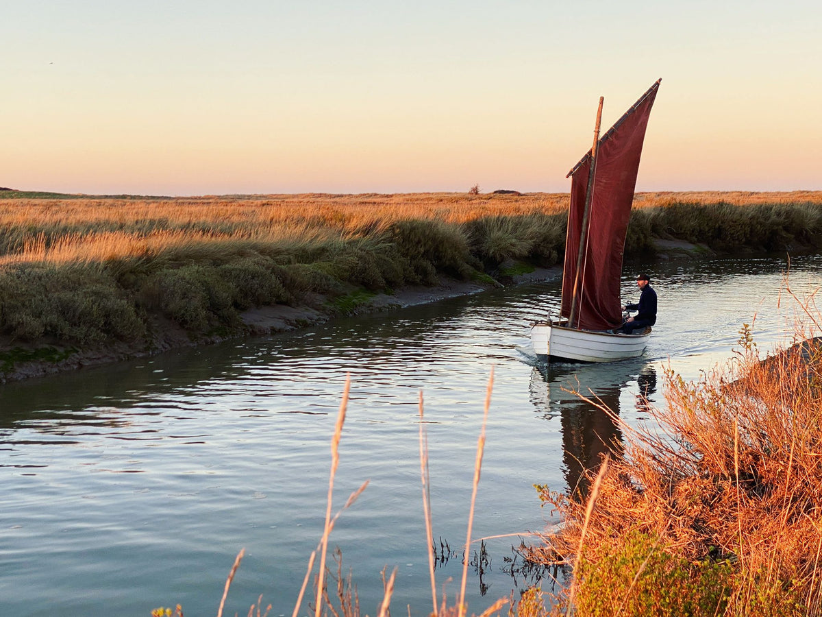 Coastal Exploration Co. mussel flat under red sail in a creek on the Wells salt marsh