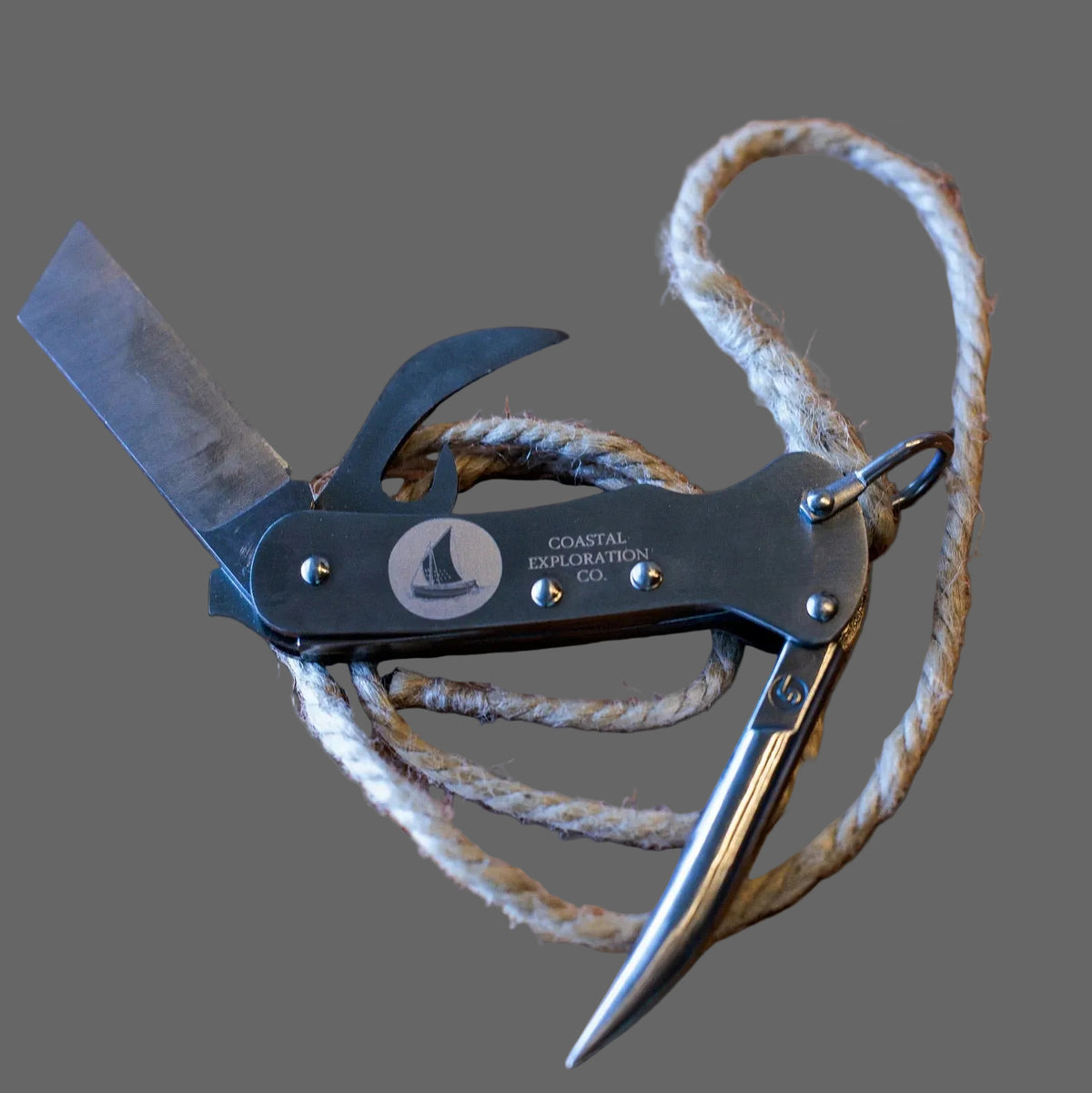 Sailor's knife with marlin spike and rope on a dark background with Coastal Exploration Co branding