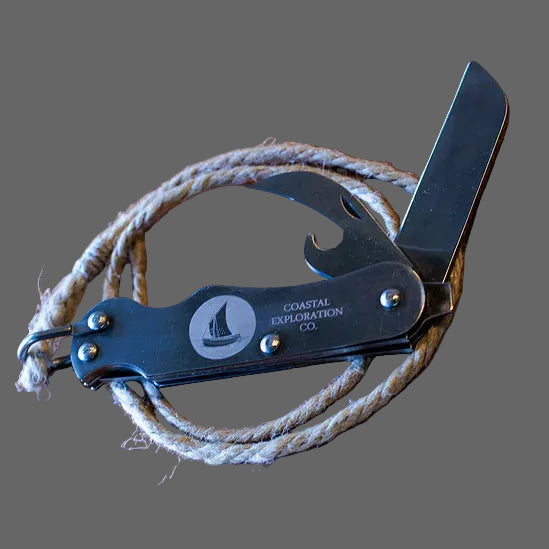 Multitool with knife, bottle opener, and screwdriver on a wooden surface with 'Coastal Exploration Co.' branding.